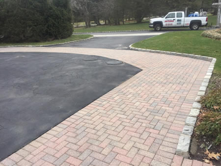 Technician pressure washing a Long Island driveway before fall