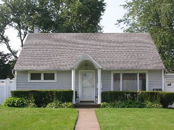 Technician pressure washing a vinyl-sided home in Long Island